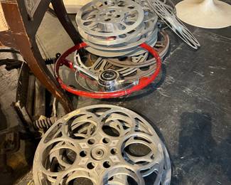 Stack of vintage metal film reels in assorted sizes. Industrial aluminum construction with classic cutout design, showing age and patina from use. Ideal for film collectors, theater décor, studio display, or industrial-style interiors. Multiple reels available.