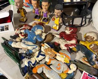 Mixed lot of collectible figurines and sports memorabilia. Includes bobbleheads, character figures, and novelty display pieces, along with decorative sculptural items. A fun assortment appealing to collectors, sports fans, and pop-culture enthusiasts.