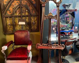 Ornate vintage floor-standing easel with carved wood construction and decorative scrollwork. Features an adjustable support and rich, dark finish with gilt-style accents. Ideal for displaying artwork, mirrors, or signage in a gallery, studio, or decorative interior.