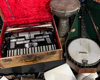 Assortment of vintage musical instruments and accessories. Includes an accordion in original case, a banjo, and a hand drum, along with related parts and cases. A unique grouping ideal for musicians, collectors, or decorative display with eclectic character.