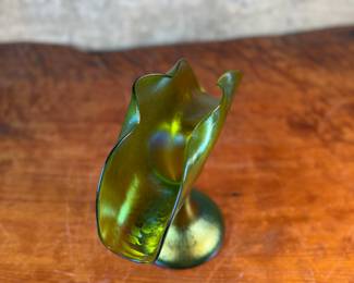 This lot features an Art Nouveau iridescent green art glass vase, likely produced by Loetz or Pallme-König between approximately 1890 and 1919. This vase measures, 9.75” H x 9.5” W x 5” D.

