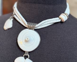 This lot features a special custom necklace by listed designer, Melanie DeLuca. Engraved sterling silver with shells & stones throughout. This piece measures, 17” and has a total approx. weight of 193.49 grams. Melanie DeLuca’s bold jewelry designs of mixed media, plastics and ethnographic objects embody a celebration of her 45 years as a metalsmith, jewelry designer and master teacher. Her interest in jewelry design began early and solidified at 17. By 20, she was apprenticing for master silversmith Brooks Darrow (himself an apprentice of renowned English architect and master metalsmith Louis Osman). Early work in painting and sculpture informed Melanie’s growing connection to the limitless expression of metal through jewelry design and fabrication.

