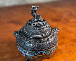 This lot features an Asian Koro, or incense burner, featuring a foo dog finial that measures, 7” H x 5” W x 5” D.

