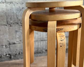 This lot features a set of three Artek Nesting Stools (model E60) in natural birch veneer, designed by Alvar Aalto. Each stool measures, 17” H x 13.5” W x 13.5” D. Designed by Alvar Aalto in 1933, the stools are a classic of Finnish modernism. They feature a patented L-shaped bent-leg construction, which makes them sturdy and easily stackable. 

