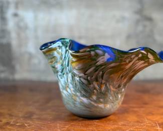 This lot features a stunning art glass vase by listed artist, Mark Russell. Signed underneath as shown in photos and measures, 7” H x 11” W x 11” D.

