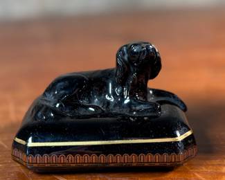 This lot features an antique English tea caddy, attributed to Henry Clay circa 1850s. It features classical Etruscan-style figures and borders with the top decorated with a reclining dog figure. This caddy measures, 5.5” H x 4.5” W x 3.5” D.

