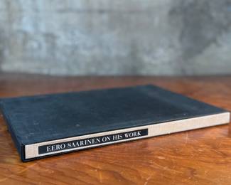 This lot features a collectible hardcover book with slipcase titled, Eero Saarinen on His Work, A Selection of Buildings. Edited by his wife, Aline Saarinen. Eero Saarinen (1910-1961) was a renowned Finnish-American architect and industrial designer, famous for his expressive, neo-futuristic structures and iconic furniture, including the Gateway Arch, TWA Flight Center, and Tulip Chairs; he was a leader in mid-century modernism, known for bold, organic forms and innovative materials, working closely with his architect father, Eliel Saarinen, before establishing his own influential firm.

