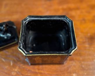 This lot features an antique English tea caddy, attributed to Henry Clay circa 1850s. It features classical Etruscan-style figures and borders with the top decorated with a reclining dog figure. This caddy measures, 5.5” H x 4.5” W x 3.5” D.

