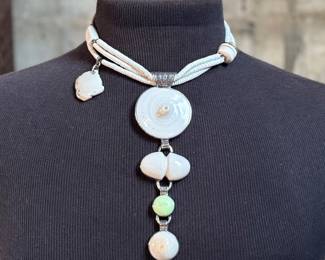 This lot features a special custom necklace by listed designer, Melanie DeLuca. Engraved sterling silver with shells & stones throughout. This piece measures, 17” and has a total approx. weight of 193.49 grams. Melanie DeLuca’s bold jewelry designs of mixed media, plastics and ethnographic objects embody a celebration of her 45 years as a metalsmith, jewelry designer and master teacher. Her interest in jewelry design began early and solidified at 17. By 20, she was apprenticing for master silversmith Brooks Darrow (himself an apprentice of renowned English architect and master metalsmith Louis Osman). Early work in painting and sculpture informed Melanie’s growing connection to the limitless expression of metal through jewelry design and fabrication.


