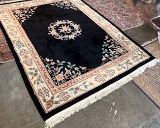 This lot features a large hand-knotted Chinese wool rug with a black and beige floral medallion design. This rug measures, 148” H x 108” W.


