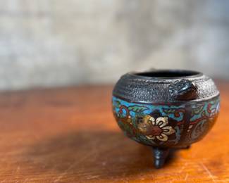 This lot features an Asian Koro, or incense burner, featuring a foo dog finial that measures, 7” H x 5” W x 5” D.

