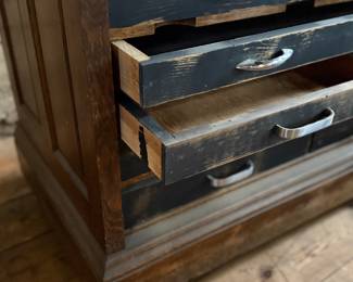 This lot features a vintage solid wood apothecary style or print maker’s cabinet. Comes on casters with multiple sized pull out drawers. The top "lift up" board is currently not attached to the backside trim, but can be easily fixed or left as is. The top cabinet area has green felt. This cabinet measures, 33.25” H x 46” W x 23” D.

