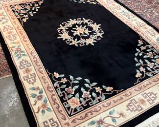 This lot features a large hand-knotted Chinese wool rug with a black and beige floral medallion design. This rug measures, 148” H x 108” W.

