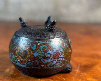 This lot features an Asian Koro, or incense burner, featuring a foo dog finial that measures, 7” H x 5” W x 5” D.

