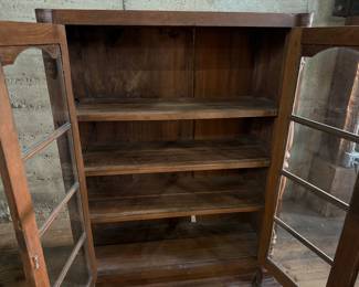 This lot features an early antique cherry wood display cabinet or bookcase. Two pieces (base is separate) with locking doors and skeleton key included. One glass pane is missing and some trim could be reattached that is included. This piece measures, 56.25” H x 42” W x 16.5” D.

