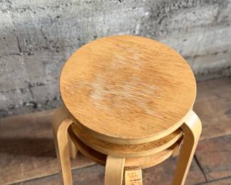 This lot features a set of three Artek Nesting Stools (model E60) in natural birch veneer, designed by Alvar Aalto. Each stool measures, 17” H x 13.5” W x 13.5” D. Designed by Alvar Aalto in 1933, the stools are a classic of Finnish modernism. They feature a patented L-shaped bent-leg construction, which makes them sturdy and easily stackable. 

