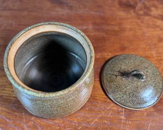 This lot features a lidded crock or jar by Richards Pottery, dated 1969. A wonderful example of studio pottery made of stoneware material and features a speckled brown glaze. This crock measures, 5” H x 6” W x 6” D.

