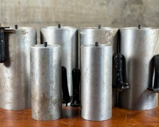 This lot features a set of six (6) cylindrical pendant lights, manufactured by Lightolier. The four larger lights measures, 8.5” H x 4” W x 4” D and the two smaller measure, 7” H x 3” W x 3” D. These lights could use some minor restoration prior to use. A beautiful set of authentic mid-century modern lighting. Lightolier was founded in 1904 by Bernhard Blitzer. Its original name was the New York Gas and Appliance Co., but it was changed to Lightolier, a combination of “light” and “chandelier, ” when electric lighting became more widely accepted.

