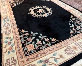 This lot features a large hand-knotted Chinese wool rug with a black and beige floral medallion design. This rug measures, 148” H x 108” W.

