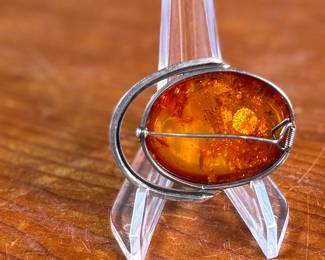 This lot features a stunning Baltic Amber in a sterling silver setting to be used as a brooch or pendant. This piece has a total approx. weight of 15.06 grams.


