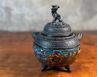 This lot features an Asian Koro, or incense burner, featuring a foo dog finial that measures, 7” H x 5” W x 5” D.

