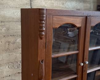 This lot features an early antique cherry wood display cabinet or bookcase. Two pieces (base is separate) with locking doors and skeleton key included. One glass pane is missing and some trim could be reattached that is included. This piece measures, 56.25” H x 42” W x 16.5” D.

