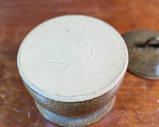 This lot features a lidded crock or jar by Richards Pottery, dated 1969. A wonderful example of studio pottery made of stoneware material and features a speckled brown glaze. This crock measures, 5” H x 6” W x 6” D.

