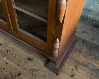 This lot features an early antique cherry wood display cabinet or bookcase. Two pieces (base is separate) with locking doors and skeleton key included. One glass pane is missing and some trim could be reattached that is included. This piece measures, 56.25” H x 42” W x 16.5” D.

