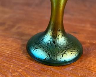 This lot features an Art Nouveau iridescent green art glass vase, likely produced by Loetz or Pallme-König between approximately 1890 and 1919. This vase measures, 9.75” H x 9.5” W x 5” D.

