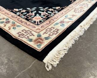 This lot features a large hand-knotted Chinese wool rug with a black and beige floral medallion design. This rug measures, 148” H x 108” W.

