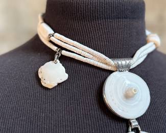 This lot features a special custom necklace by listed designer, Melanie DeLuca. Engraved sterling silver with shells & stones throughout. This piece measures, 17” and has a total approx. weight of 193.49 grams. Melanie DeLuca’s bold jewelry designs of mixed media, plastics and ethnographic objects embody a celebration of her 45 years as a metalsmith, jewelry designer and master teacher. Her interest in jewelry design began early and solidified at 17. By 20, she was apprenticing for master silversmith Brooks Darrow (himself an apprentice of renowned English architect and master metalsmith Louis Osman). Early work in painting and sculpture informed Melanie’s growing connection to the limitless expression of metal through jewelry design and fabrication.

