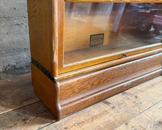 This lot features a stacking barrister bookcase manufactured by Globe Wernicke, dating back to the early 1900s. This bookcase in particular has a total of seven (7) pieces – 5 stacking bookcases, a base, and a topper. This piece measures from top to bottom, 75” H x 34” W x 11” D.

