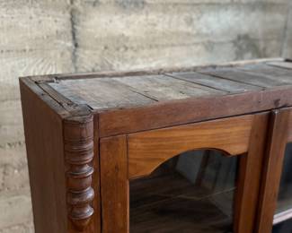 This lot features an early antique cherry wood display cabinet or bookcase. Two pieces (base is separate) with locking doors and skeleton key included. One glass pane is missing and some trim could be reattached that is included. This piece measures, 56.25” H x 42” W x 16.5” D.

