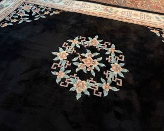 This lot features a large hand-knotted Chinese wool rug with a black and beige floral medallion design. This rug measures, 148” H x 108” W.

