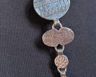 This lot features a special custom necklace by listed designer, Melanie DeLuca. Engraved sterling silver with shells & stones throughout. This piece measures, 17” and has a total approx. weight of 193.49 grams. Melanie DeLuca’s bold jewelry designs of mixed media, plastics and ethnographic objects embody a celebration of her 45 years as a metalsmith, jewelry designer and master teacher. Her interest in jewelry design began early and solidified at 17. By 20, she was apprenticing for master silversmith Brooks Darrow (himself an apprentice of renowned English architect and master metalsmith Louis Osman). Early work in painting and sculpture informed Melanie’s growing connection to the limitless expression of metal through jewelry design and fabrication.

