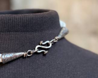 This lot features a special custom necklace by listed designer, Melanie DeLuca. Engraved sterling silver with shells & stones throughout. This piece measures, 17” and has a total approx. weight of 193.49 grams. Melanie DeLuca’s bold jewelry designs of mixed media, plastics and ethnographic objects embody a celebration of her 45 years as a metalsmith, jewelry designer and master teacher. Her interest in jewelry design began early and solidified at 17. By 20, she was apprenticing for master silversmith Brooks Darrow (himself an apprentice of renowned English architect and master metalsmith Louis Osman). Early work in painting and sculpture informed Melanie’s growing connection to the limitless expression of metal through jewelry design and fabrication.

