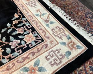 This lot features a large hand-knotted Chinese wool rug with a black and beige floral medallion design. This rug measures, 148” H x 108” W.

