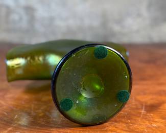 This lot features an Art Nouveau iridescent green art glass vase, likely produced by Loetz or Pallme-König between approximately 1890 and 1919. This vase measures, 9.75” H x 9.5” W x 5” D.

