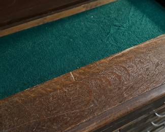 This lot features a vintage solid wood apothecary style or print maker’s cabinet. Comes on casters with multiple sized pull out drawers. The top "lift up" board is currently not attached to the backside trim, but can be easily fixed or left as is. The top cabinet area has green felt. This cabinet measures, 33.25” H x 46” W x 23” D.

