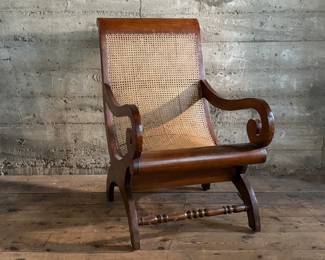 This lot features a British Colonial style plantation lounge chair with a matching ottoman in very good overall condition. The chair measures, 41” H x 24.5” W x 33” W.

