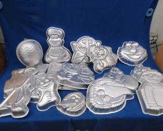 Lot 367. 15 character-shaped cake pans many are made in Korea for Wilton, several are Sesame Street themed, Matel He Man, Popeye, and more