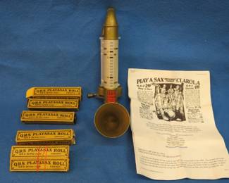 Lot 156. Vintage Q.R.S. De Vry Corp. Playsax Clarola with six rolls. There is a broken piece beneath where the rolls attach. Minimum bid $50.