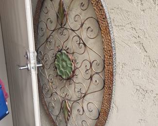 Impressive oval metal wall hanging featuring hammered copper-tone border, elegant wrought iron scrolls, and dimensional green succulent bloom in the center. Perfect outdoor or indoor Southwest decor.

