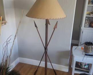 Vintage Southwestern-style floor lamp with a metal arrow motif base, and tripod-style legs, featuring decorative arrowhead and fletching details. 