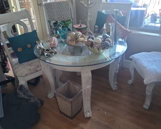 Coastal chic living room packed with treasures: glass-top carved white pedestal table loaded with seashell orbs, nautical decor, vases, and collectibles; distressed white chairs, woven baskets, plush throws, large lamp, and more. So much unique home decor throughout this Gilbert estate!