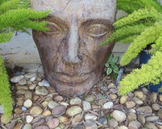 Carved stone head between to foxtail plants.