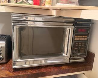 Vintage Amana Radarange Microwave – Touchmatic Series
Classic Amana Radarange countertop microwave with Touchmatic electronic controls. Heavy-duty construction with chrome and black exterior, glass turntable, and original control panel. Tested and powers on; heats properly. Shows cosmetic wear consistent with age and use. A solid example of early consumer microwave design—great for collectors, retro kitchens, or display.