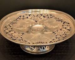 Antique Whiting Pierced Sterling Silver Footed Dish 

Offered is an antique Whiting pierced sterling silver footed dish featuring intricate floral and scrollwork patterns cut into the silver. The dish has a diameter of approximately 12 inches and stands about 4 inches high. Total weight is 734 grams. There are some bends and dents present. A central monogram is engraved. See pictures for more details on the decorative details and condition.

Features:
Sterling silver construction
Pierced decorative pattern
Footed base
Floral and scrollwork motifs
Monogrammed center
Measures approx. 12" diameter x 4" high
Weighs 734 grams