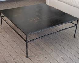 Large Iron and Slate Coffee Table 40 x 40 Inches

This is a large coffee table featuring an iron frame and a slate top. The table measures approximately 40 inches by 40 inches with a height of 15 inches. The top shows some marks and discoloration, consistent with prior use. The sturdy iron legs include a twisted detail at the bottom, adding character to the piece.