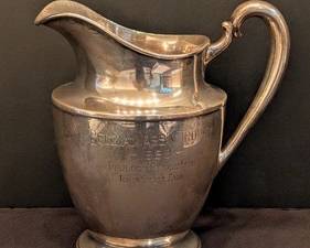 Antique 1928 Wallace Sterling Silver Trophy Pitcher Belgian Ass'n Iowa State Fair

This vintage Wallace sterling silver trophy pitcher features an inscription commemorating the 1928 Belgian Ass'n Trophy awarded to Boulder Bridge Farm at the Iowa State Fair. Crafted from sterling silver with the Wallace hallmark, the pitcher stands approximately 8.5 inches high and 8 inches wide. The total weight is 624 grams. The piece displays charming patina, light surface wear, and engraved details characteristic of a well-preserved antique.

Features:
Original 1928 inscription for Belgian Ass'n Trophy
Sterling silver, marked Wallace 4883, 4 PTS
Dimensions: 8.5 in high x 8 in wide
Total weight: 624 grams
See pictures for more details.